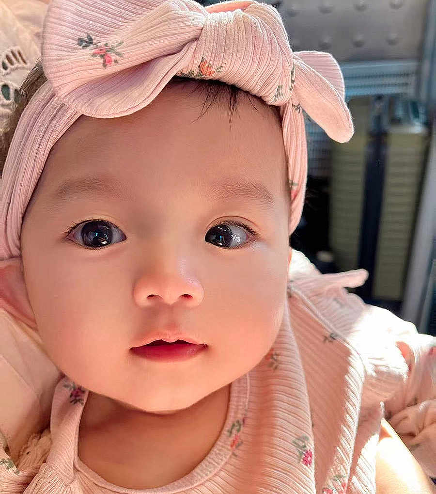 Hanna is registered to the contest to win money with this photo: baby, child, face, headband, pink, closeup, portrait, cute, infant, young_child, apparel, bow, soft_light, indoors, person, skin, eyelashes, expression, adorable, fashion