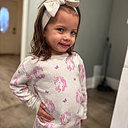 Aria Rose is registered to the contest to win money with this photo: child, girl, pajamas, unicorn, headband, bow, smile, pose, indoors, floor, wall, door, hand_on_hip, long_hair, cute, happy, person, clothing, portrait, home