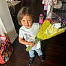 child, boy, flowers, bouquet, indoor, smile, jeans, tshirt, toy, gumball_machine, coat, minnie_mouse, bag, wooden_floor, plant, home, playful, standing, happy, casual_clothing