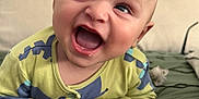 Theo joined the competition — help win amazing prizes! baby, child, smiling, happy, face, eyes, mouth, clothing, blanket, bed, pillow, indoor, infant, cute, expression, skin, head, person, lying, blue_wall