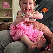 Journey is registered to the contest to win money with this photo: baby, child, smiling, tutu, headband, pink, clothing, person, hands, feet, indoor, sitting, adult_hand, furniture, decor, balloon_dog, sign, love_message, cozy, portrait