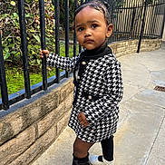 Bella joined the competition — help win amazing prizes! toddler, child, black_and_white_coat, houndstooth, leggings, white_shoes, outdoor, sidewalk, iron_fence, stone_wall, greenery, curious_expression, standing, fashionable, urban, person, portrait, young_child, baby, cute