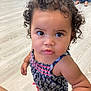 toddler, child, curly_hair, indoor, floor, person, blue_outfit, patterned_clothing, barefoot, looking_up, cute, skin, face, eyes, expression, standing, casual, people, home, furniture