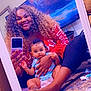 woman, baby, mirror, selfie, curly_hair, red_shirt, blue_onesie, carpet, couch, television, living_room, smile, holding, sitting, foot, bracelet, phone, reflection, indoor, person