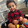 toddler, child, curly_hair, smiling, red_shirt, black_and_red_checkered, toy_car, indoor, bed, window, blinds, mesh_chair, playful, cute, happy, person, skin, sitting, furniture, toy
