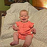 Margaret is registered to the contest to win money with this photo: baby, infant, child, smiling, laughing, portrait, sitting, coral_outfit, dress, blanket, couch, cushion, indoor, home, window, wooden_blinds, warm_lighting, patterned_fabric, happy, photography