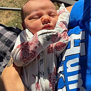 Aria is registered to the contest to win money with this photo: baby, sleeping, infant, floral_pajamas, hand, tattoo, blue_shirt, outdoor, sunlight, grass, chair, person, closeup, peaceful, portrait, newborn, cute, resting, skin, relaxation