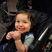 Michael joined the competition — help win amazing prizes! baby_gear, blue_pants, candid, carpet, chair, child, clothing, eyes, face, gray_shirt, hair, hands, happy, indoors, portrait, seated, smiling, stroller, toddler, travel