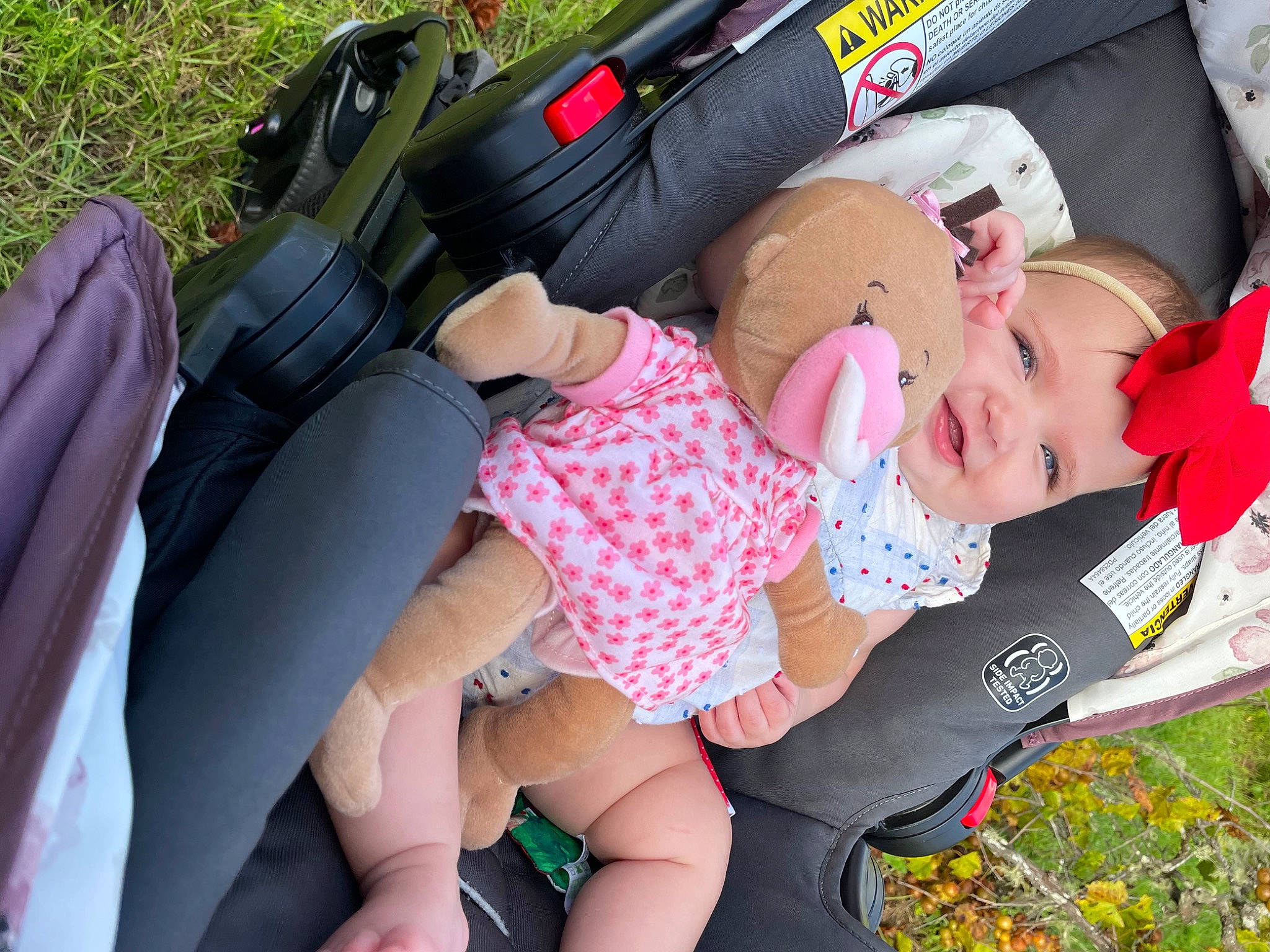 Adaline is registered to the contest to win money with this photo: baby, baby_toddler_clothing, car_seat, child, comfort, finger, fun, grass, hand, headwear, human_leg, joy, lap, leg, pattern, person, pink, plant, shorts, thigh