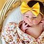 baby, newborn, bow, headband, wicker_basket, blanket, swaddle, floral_pattern, infant, portrait, cute, rosy_cheeks, hand, face, eyes, skin, cozy, soft_texture, wood_floor, closeup