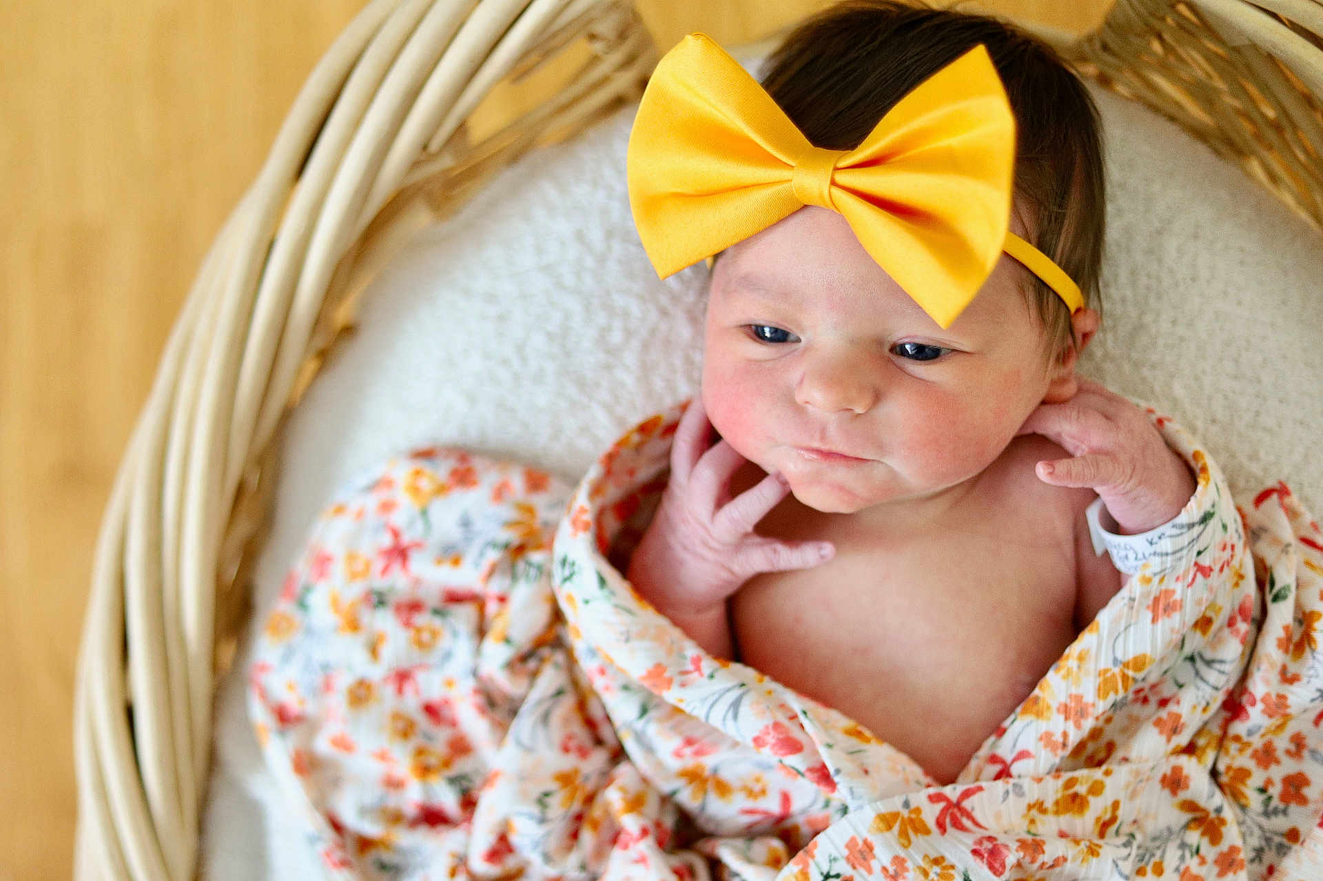 Trinity is registered to the contest to win money with this photo: baby, newborn, bow, headband, wicker_basket, blanket, swaddle, floral_pattern, infant, portrait, cute, rosy_cheeks, hand, face, eyes, skin, cozy, soft_texture, wood_floor, closeup