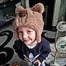 child, smiling, hat, bear_hat, blue_eyes, sweatshirt, indoor, toy, baby_gear, carpet, person, cute, playful, young_child, face, headwear, clothing, happy, portrait, home