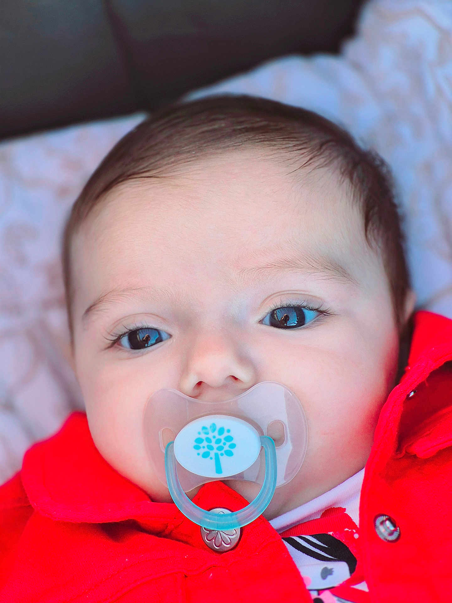 Chloé participe au concours pour gagner de l'argent avec cette photo : baby, pacifier, red_jacket, closeup, face, eyes, infant, child, blanket, cute, portrait, young, skin, clothing, babywear, lying_down, indoors, soft_light, head, expression