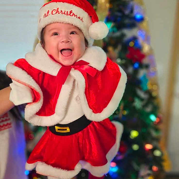 Arabella joined the competition — help win amazing prizes! baby, babylaughing, christmas, christmasdecorations, christmastree, clothing, coat, costume, face, festival, happy, hat, head, lighting, person, photography, portrait, santaclaus