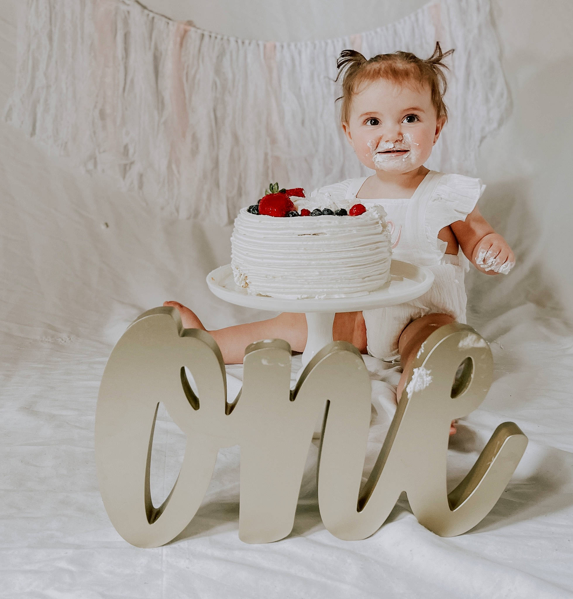 Addyson is registered to the contest to win money with this photo: baby_toddler_clothing, buttercream, cake, cake_decorating, cake_decorating_supply, cake_stand, font, happy, headgear, headpiece, icing, party_supply, person, petal, serveware, smile, sugar_cake, sugar_paste, table, toddler