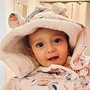 Lizyo a rejoint le concours — aidez-le/la à gagner de superbes lots ! baby, child, hood, coat, jacket, turtle_pattern, indoor, smile, face, curious, warm_clothing, cute, infant, portrait, soft_lighting, closeup, apparel, button, babywear, young_child