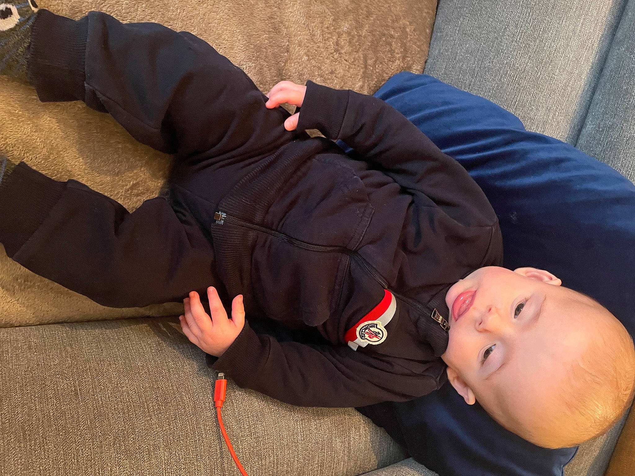 Lucca is registered to the contest to win money with this photo: arm, comfort, elbow, finger, grass, hand, human, human_body, human_leg, joint, knee, lap, leg, person, sitting, sleeve, smile, thigh, toddler, vertebrate