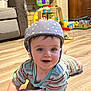 Youenn a rejoint le concours — aidez-le/la à gagner de superbes lots ! baby, helmet, smile, floor, toy, living_room, child, striped_clothing, crawling, happy, indoor, person, face, wooden_floor, play, cute, infant, helmet_pattern, colorful, background