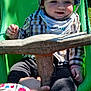 toddler, child, swing, hat, plaid_shirt, outdoor, playground, green, sunlight, smile, baby, person, hand, clothing, safety_bar, grass, daylight, play, interaction, park