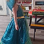 child, dress, princess_costume, blue_dress, green_lace, gold_accent, indoor, wooden_floor, table, toy_storage, toys, furniture, young_child, costume, playroom, side_view, long_dress, child_playing, home, floor