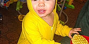 Frankie is registered to the contest to win money with this photo: activity_center, baby_snack, blanket, bookcase, brown_eyes, carpet_floor, child, face, hand, hood, indoor, playroom, portrait, red_plate, smile, toddler, toys, waffle, yellow_hoodie, zipper