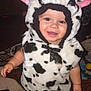 baby, barefoot, carpet, child, clothing, costume, cow_costume, ears, eyes, face, flash_photography, fuzzy, grin, hand, hood, indoor, plush, smile, toddler, toy