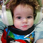 Frankie is registered to the contest to win money with this photo: child, toddler, baby_face, headphones, oversized_headphones, curly_hair, close_up, portrait, pajamas, mickey_mouse, cartoon_character, festive, indoors, parent_peek, glasses, cable, cheeks, adorable, cozy, playful