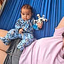 adult, baby, blue, casual, child, clothing, cow_toy, cute, fabric, hammock, infant, laying_down, onesie, outdoor, penguin_pattern, person, plush_toy, portrait, relaxing, resting