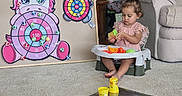 Udaya joined the competition — help win amazing prizes! booster_chair, carpet, child, colorful, concentration, couch, craft, dartboard, elephant, girl, indoors, modeling_clay, pink_dress, play_dough, playroom, portrait, sitting, toddler, toy, unicorn