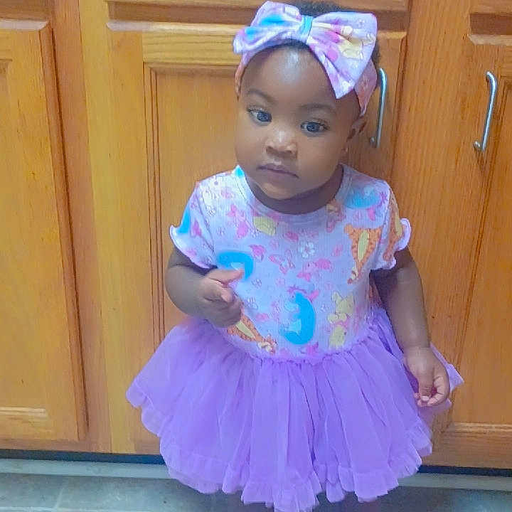 Mi'Zyae joined the competition — help win amazing prizes! toddler, child, girl, purple_tutu, headband, bow, sandals, kitchen, cabinets, floor, tile_floor, standing, clothing, indoor, person, cute, baby, young_child, footwear, curious