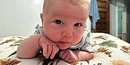 Hudson is registered to the contest to win money with this photo: baby, infant, face, hands, pillow, patterned, indoor, curious, skin, eyes, head, clothing, short_hair, room, door, towel, wood, furniture, closeup, lying