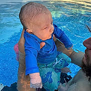 Hudson joined the competition — help win amazing prizes! baby, child, swimwear, pool, water, adult, holding, summer, outdoor, blue, swimming, person, skin, head, face, wet, reflection, calm, ripples, sunlight