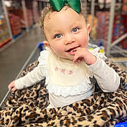 Ariyah joined the competition — help win amazing prizes! child, toddler, shopping_cart, blanket, leopard_print, bow, green_bow, curly_hair, blue_eyes, cute, baby, clothing, long_sleeves, indoor, aisle, store, retail, portrait, smiling, hand