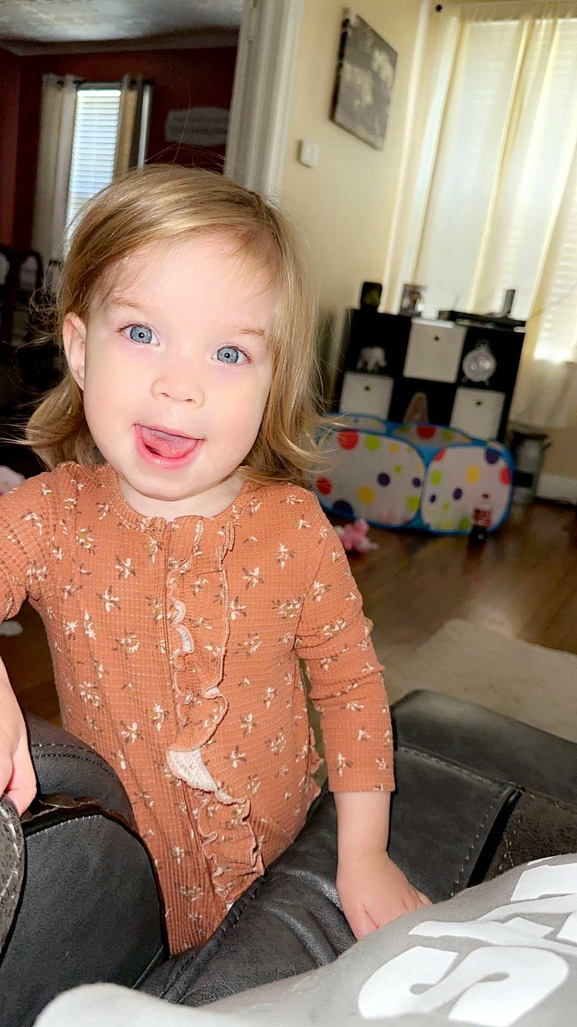 Constance is registered to the contest to win money with this photo: baby_toddler_clothing, blond, brown_hair, cheek, comfort, flooring, happy, human_leg, iris, knee, lap, lip, long_hair, person, picture_frame, sitting, skin, smile, thigh, toddler