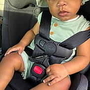 Camden is registered to the contest to win money with this photo: toddler, child, car_seat, seatbelt, hat, green_clothing, baby, safety, car_interior, serious_expression, hand, leg, sunlight, portrait, seat, young_child, cute, travel, infant, sitting