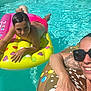 child, adult, swimming_pool, float, inflatable, water, sunlight, swimwear, smile, sunglasses, tattoo, relaxation, summer, fun, outdoor, leisure, vacation, bright_colors, heart_shapes, donut_float