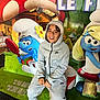 child, smiling, hoodie, tracksuit, nike, cap, indoor, smurfs, cartoon, colorful, poster, playful, happy, seated, casual_clothing, young, person, background, illustration, fun