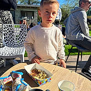 Côme participe au concours pour gagner de l'argent avec cette photo : child, boy, outdoor, table, snacks, party, popcorn, cup, people, sweater, sunlight, grass, chair, adult, conversation, daylight, casual_clothing, party_food, relaxing, background