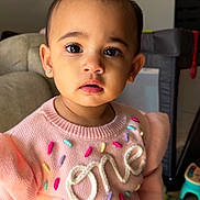 Kaavya joined the competition — help win amazing prizes! toddler, child, pink_sweater, indoor, cute, curious, face, portrait, expression, knitwear, earrings, young_child, colorful, sprinkles, standing, bow, home, carpet, furniture, play_area