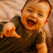 Liliana joined the competition — help win amazing prizes! baby, smiling, laughing, child, happy, infant, cute, portrait, reaching_hand, blanket, cozy, warm_lighting, soft_texture, indoor, casual_clothing, short_hair, closeup, face, expression, toddler