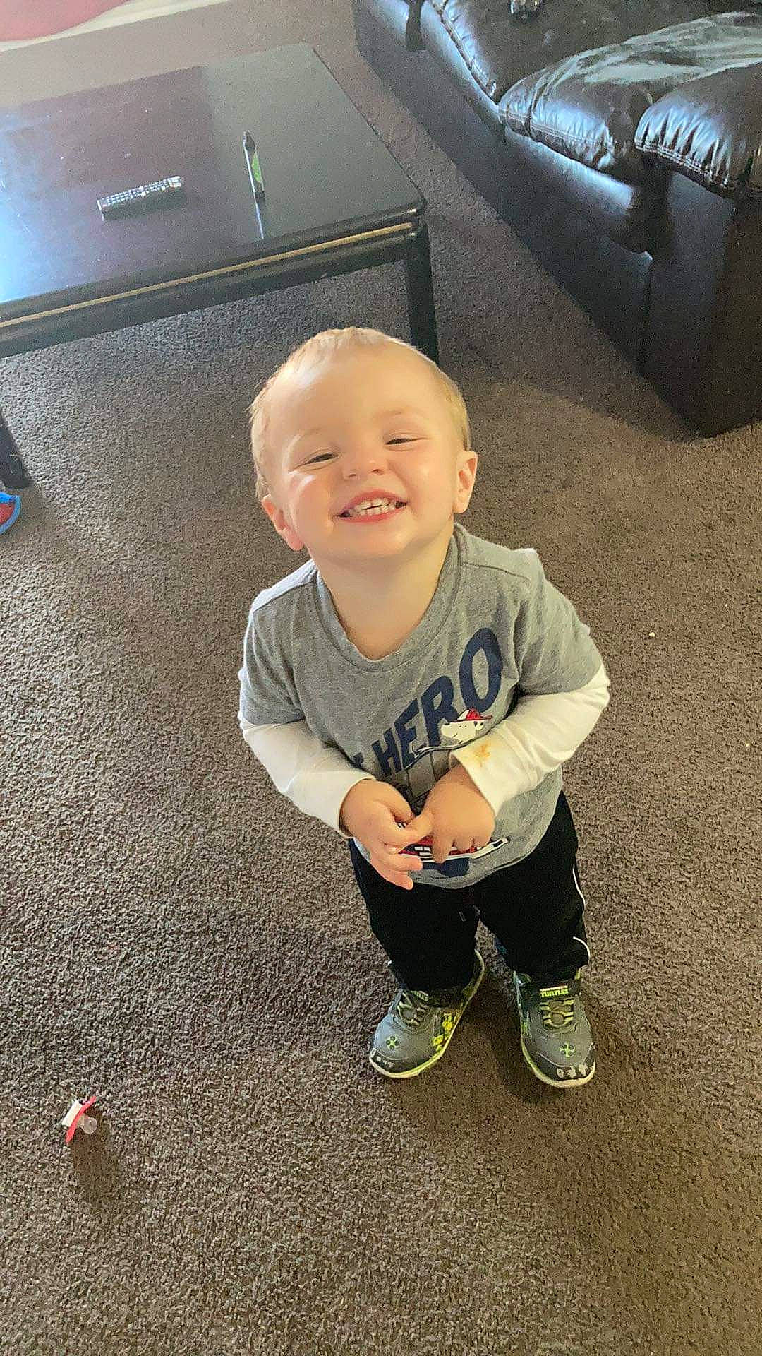 Karson is registered to the contest to win money with this photo: automotive_exterior, automotive_tire, baby_toddler_clothing, cool, finger, floor, flooring, hairstyle, happy, head, joy, leg, person, shoe, sleeve, smile, sneakers, standing, tints_and_shades, toddler