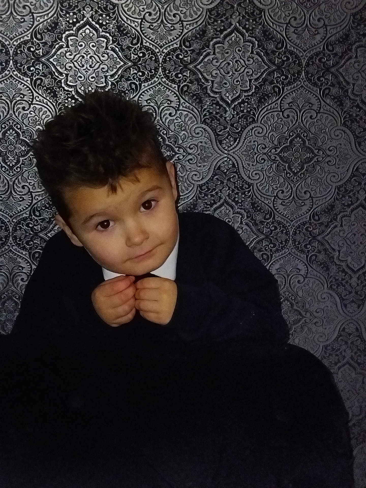 Dannylee joined the competition — help win amazing prizes! boy, brown_eyes, casual_clothing, child, closeup, curly_hair, cute, dark_sweater, expression, face, hair, hands, indoor, looking_at_camera, patterned_wallpaper, person, portrait, sitting, skin, young