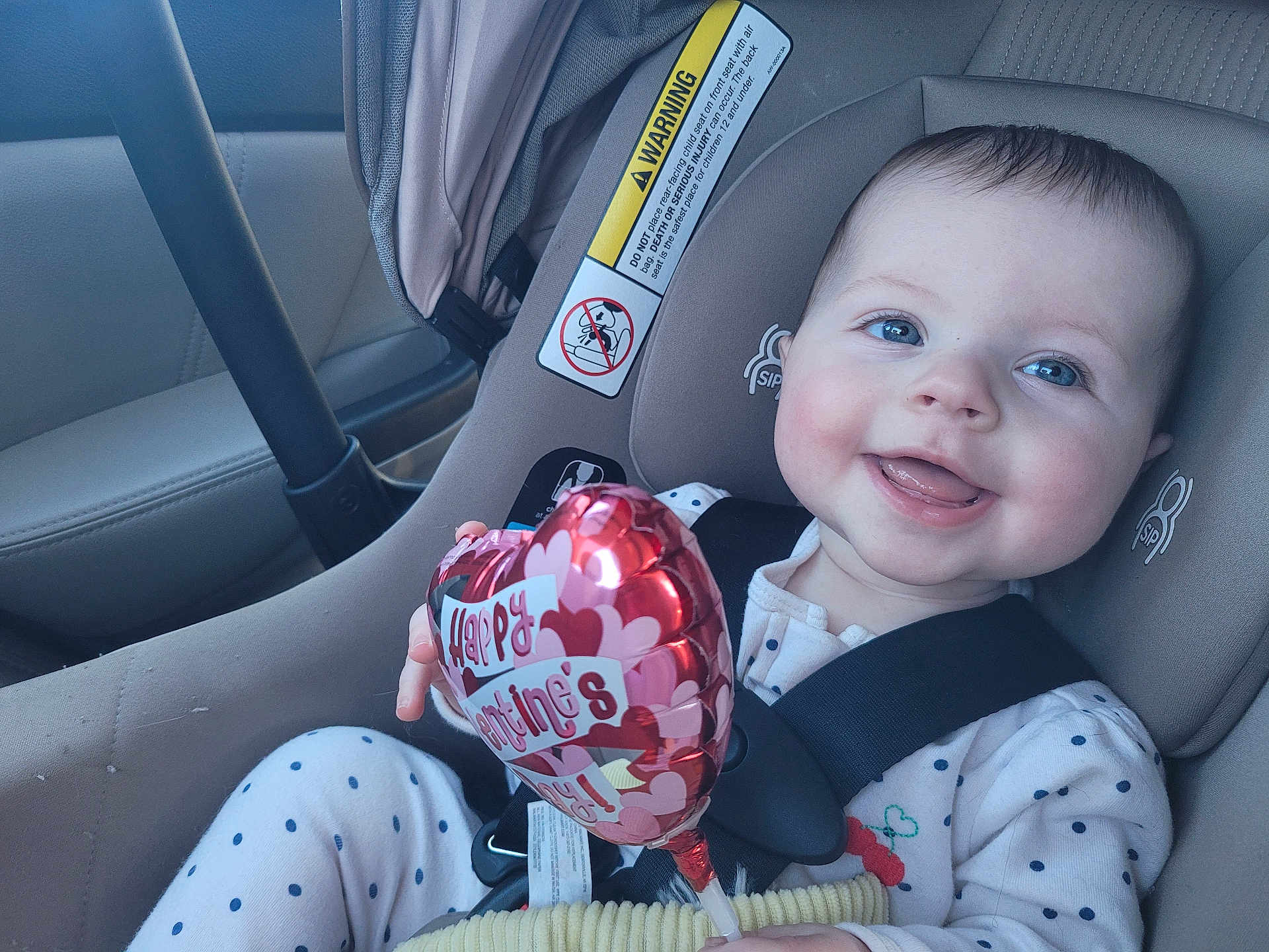 Joanna joined the competition — help win amazing prizes! baby, infant, child, car_seat, seatbelt, valentine_balloon, smiling, blue_eyes, polka_dot_pajamas, happy, cheeks, hand, car_interior, warning_label, closeup, portrait, sitting, toy, window, skin