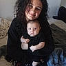 Caden is registered to the contest to win money with this photo: child, baby, smile, curly_hair, black_clothing, bed, blanket, indoor, person, family, cuddle, portrait, young_girl, infant, holding, cozy, casual, cute, toddler, soft_lighting