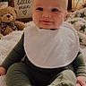 baby, infant, child, smiling, sitting, portrait, bib, blanket, teddy_bear, stuffed_animal, nursery, cozy, pillow, plant, indoor, home, baby_clothing, happy, face, photography