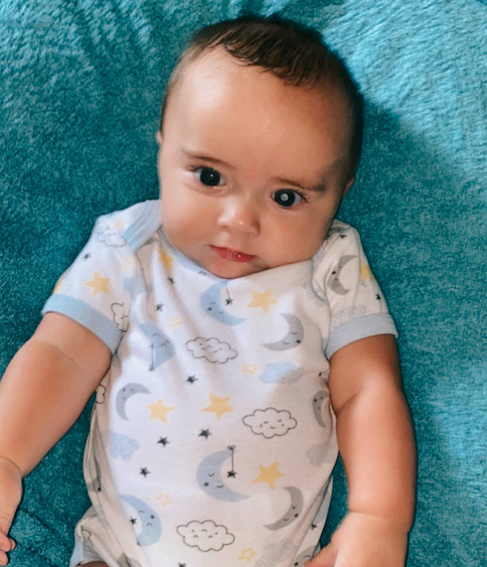 Rayden is registered to the contest to win money with this photo: azure, baby, baby_products, baby_toddler_clothing, cheek, child, collar, comfort, electric_blue, iris, linens, lip, neck, nose, pattern, person, sitting, skin, sleeve, t_shirt