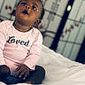 baby, child, infant, pink_onesie, clothing, face, hands, bed, white_bedspread, indoor, portrait, sitting, looking_up, curious, expression, skin, person, young_child, cute, soft_light