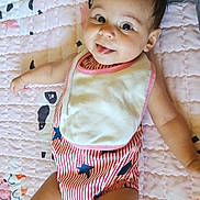 Rye joined the competition — help win amazing prizes! baby, child, infant, smiling, tongue_out, striped_clothing, bib, quilt, pink, animal_pattern, lying_down, cute, happy, cheerful, indoor, person, skin, head, face, arm