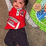 baby, infant, carpet, play_mat, wooden_marker, four_months, red_shirt, gray_sleeves, black_pants, tattoo, bare_feet, child, smiling, lying_down, indoors, cute, milestone, person, floor, hand