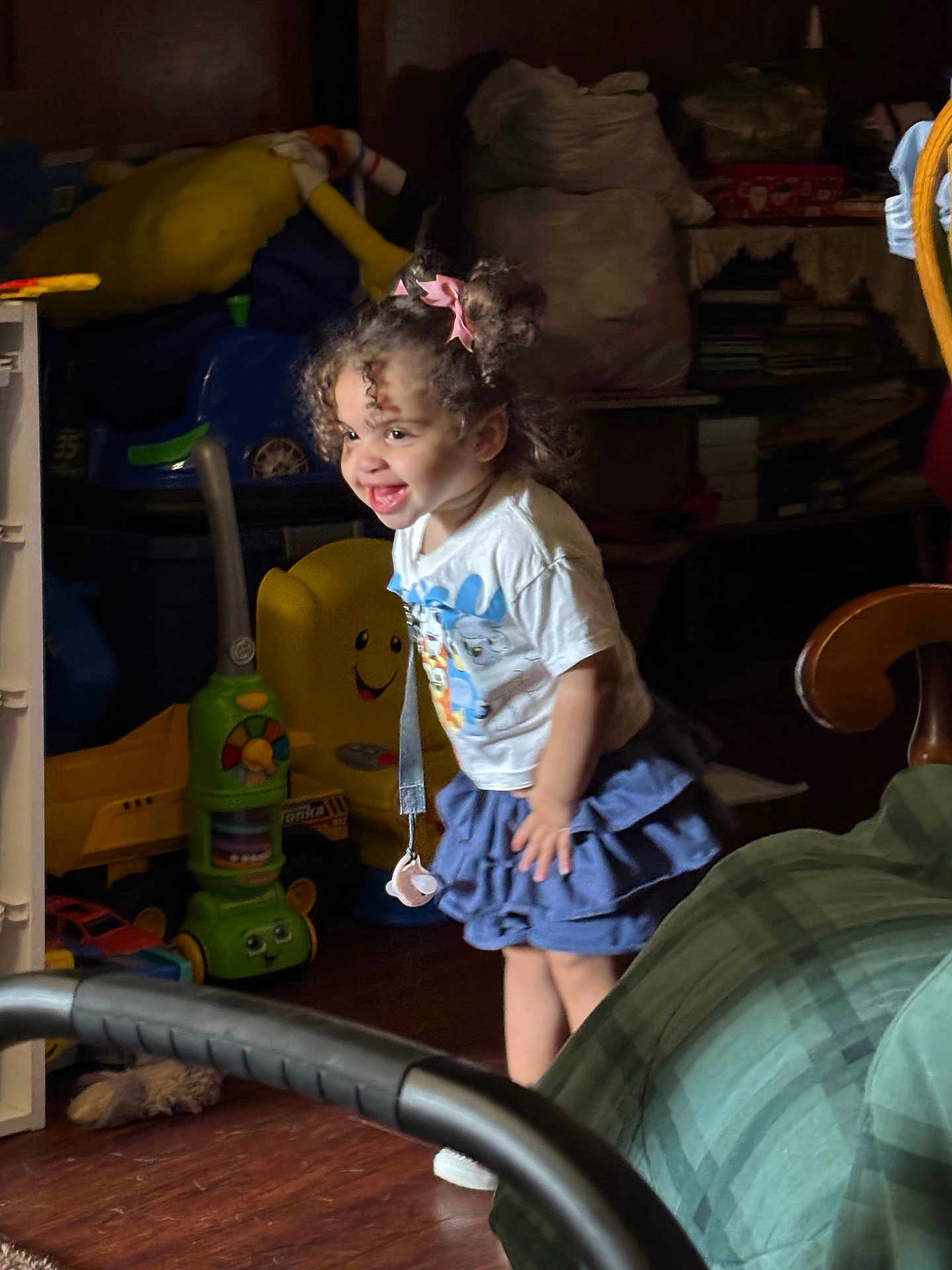 Jenna joined the competition — help win amazing prizes! child, toddler, smiling, curly_hair, pink_bows, white_shirt, blue_skirt, toy, indoor, wooden_floor, happy, playful, person, furniture, household_items, colorful, young_child, cute, joyful, standing